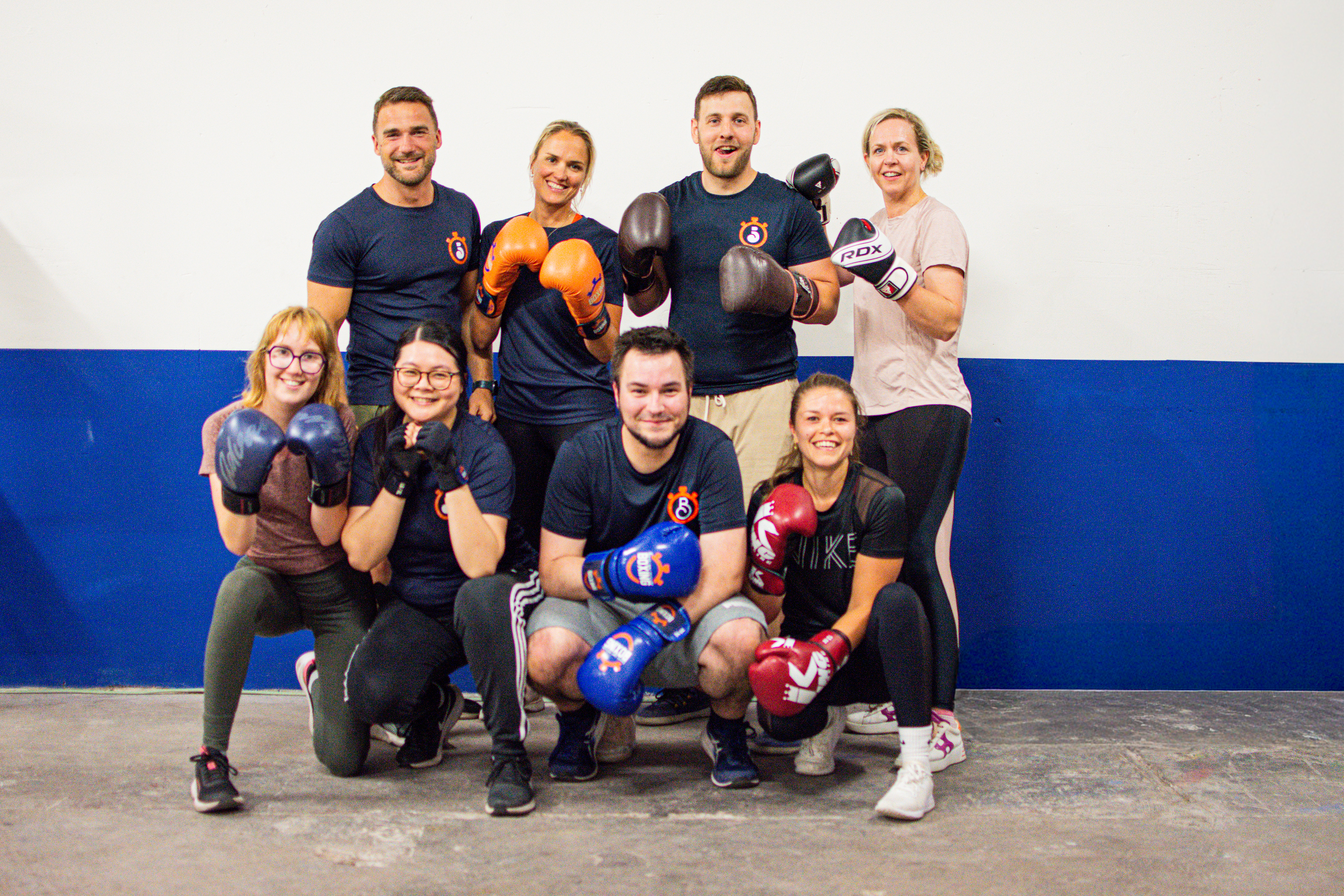 Een uitgelaten groep van veertien leden met bokshandschoenen aan, samen op de foto na een training